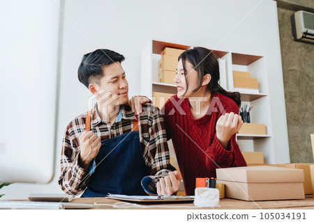 A young Asian couple shows delight and smiles on their faces when they see the sales volume and customer orders exceed expectations. sme or small business family concepts. 105034191