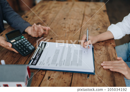 Guarantee, mortgage, contract, contract, signed, real estate agent or bank officer holding a calculator, submits a bid with a customer to buy a home before signing to make a deal. Guarantee, mortgage, contract, contract, signed, real estate agent or bank officer holding a calculator, submits a bid with a customer to buy a home before signing to make a deal. 105034192