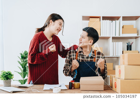 A young Asian couple shows delight and smiles on their faces when they see the sales volume and customer orders exceed expectations. sme or small business family concepts. 105034197