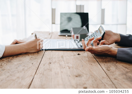 Guarantee, mortgage, contract, contract, signed, real estate agent or bank officer holding a calculator, submits a bid with a customer to buy a home before signing to make a deal. Guarantee, mortgage, contract, contract, signed, real estate agent or bank officer holding a calculator, submits a bid with a customer to buy a home before signing to make a deal. 105034255