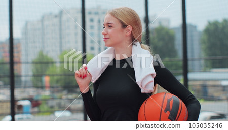 Portrait of woman with basket ball looking at the camera on basketball court. Girl playing basketball on the court. Concept of sport, power, competition, active lifestyle. Portrait of woman with basket ball looking at the camera on basketball court. Girl playing basketball on the court. Concept of sport, power, competition, active lifestyle. 105035246