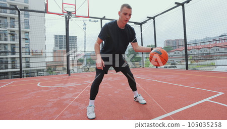 Male basketball player practicing ball handling skill on basketball court. Man basketball player training alone. Workout. Sport activities. 105035258