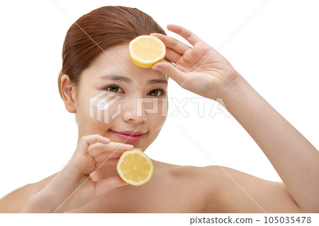 beautiful young woman with clean skin, moisturizing cream and holding a lemon 105035478