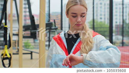 Young fitness woman looking at smartwatch outdoors athlete training equipment app. Healthy lifestyle concept. 105035608