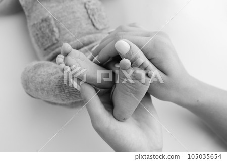 The palms of the father, the mother are holding the foot of the newborn baby on white background. Feet of the newborn on the palms of the parents. Photography of a child's toes, heels and feet. The palms of the father, the mother are holding the foot of the newborn baby on white background. Feet of the newborn on the palms of the parents. Photography of a child's toes, heels and feet. 105035654