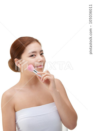 clean-skinned female model holding a makeup brush against a white background clean-skinned female model holding a makeup brush against a white background 105036011