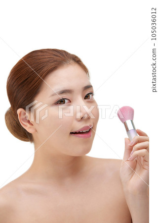 clean-skinned female model holding a makeup brush against a white background clean-skinned female model holding a makeup brush against a white background 105036012