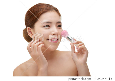 clean-skinned female model holding a makeup brush against a white background 105036013