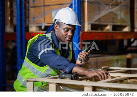 Male american african engineer holding walkie talkie and tablet quality control standing at machine. 105036078
