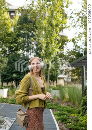 Portrait of a happy girl listening music on line with wireless headphones from a smartphone in the street in a summer sunny day Portrait of a happy girl listening music on line with wireless headphones from a smartphone in the street in a summer sunny day 105036090