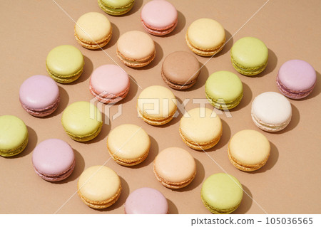 An overhead shot of a beige table surface featuring an array of colorful macarons in neat rows An overhead shot of a beige table surface featuring an array of colorful macarons in neat rows 105036565