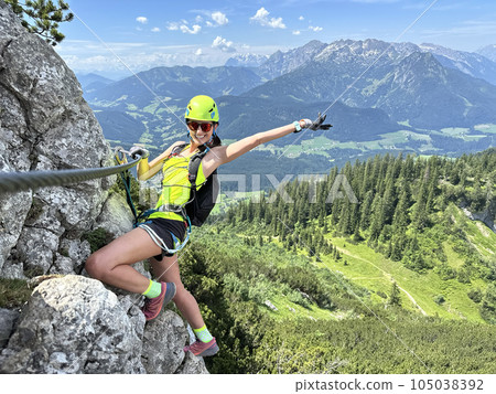Female climber on a via ferrata - climbing on a rock in Austria Alps Female climber on a via ferrata - climbing on a rock in Austria Alps 105038392