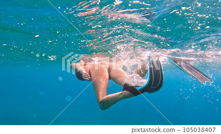 Brunette woman with snorkeling mask and tube swimming in the sea. Underwater view. 105038407