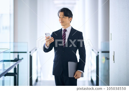 A middle-class businessman in a suit who operates a smartphone in the office 105038550