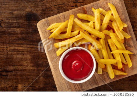 French fries, potato snack with ketchup, fast food on a wooden table 105038580