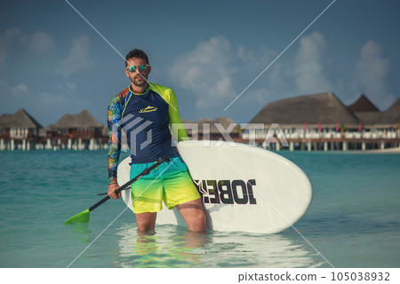 attractive man on a paddle board in a tropical resort, active vacation and healthy style in the Maldives attractive man on a paddle board in a tropical resort, active vacation and healthy style in the Maldives 105038932