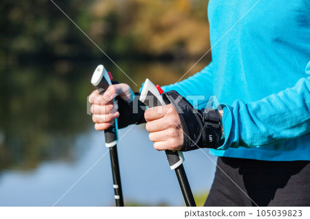 Nordic walking exercise adventure hiking concept - closeup of woman's hand holding nordic walking poles Nordic walking exercise adventure hiking concept - closeup of woman's hand holding nordic walking poles 105039823