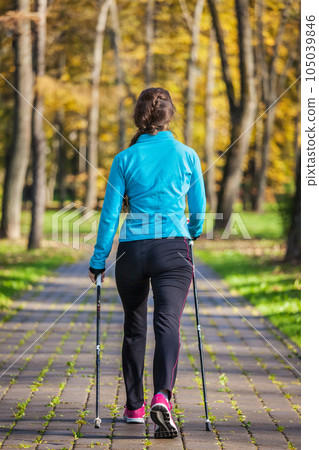 Nordic walking adventure and exercising concept - woman hiking withnordic walking poles in park 105039846