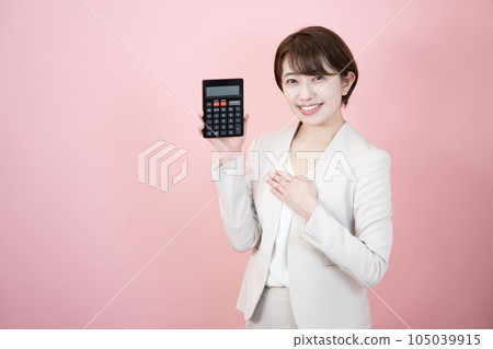 一個微笑的女人拿著一個粉紅色背景的黑色計算器 105039915
