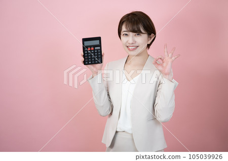 一個微笑的女人拿著一個粉紅色背景的黑色計算器 105039926