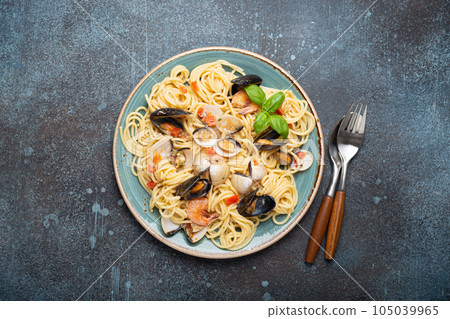 Italian seafood pasta spaghetti with mussels, shrimps, clams in tomato sauce with green basil on plate on rustic blue concrete background top view. Mediterranean cuisine 105039965
