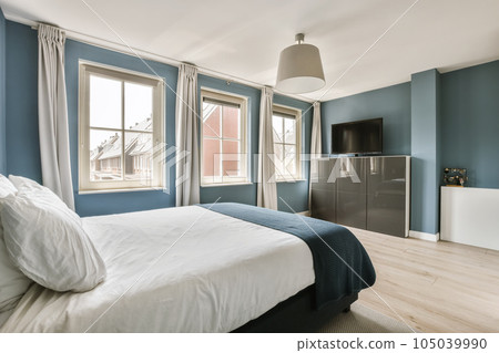 a bedroom with blue walls and white bedding in front of a tv set on the wall above the bed 105039990