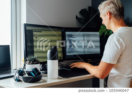 Focus on shaker with dry dehydrated meal on the desk of young man working on pc. IT specialist programmer eating during work. Balanced nutritionally complete meals diet. Food replacement. Biohacking 105040047
