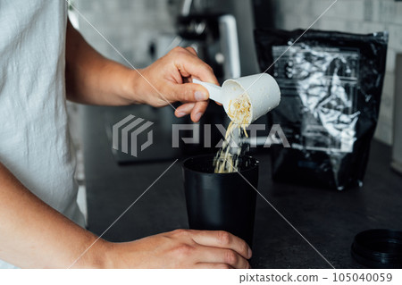 Close up male hand pouring dry dehydrated meal into pot with background of bags with balanced nutritionally complete meals on kitchen table. Food replacement, plant based protein. Biohacking. 105040059