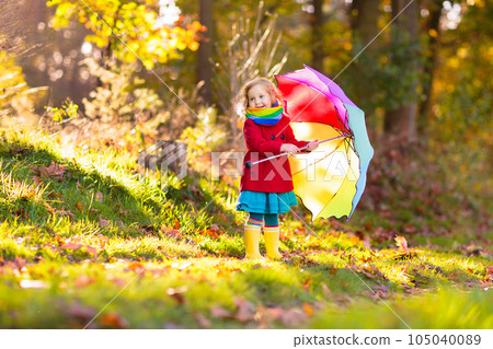 Kid with umbrella playing in autumn rain. 105040089