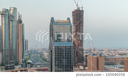 Dubai city skyline panoramic view with metro and cars moving on city's busiest highway aerial night to day timelapse 105040356