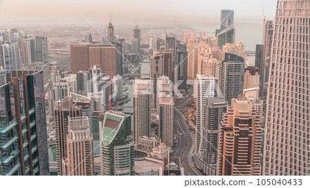 Skyline view of Dubai Marina showing canal surrounded by skyscrapers along shoreline night to day timelapse. DUBAI, UAE 105040433