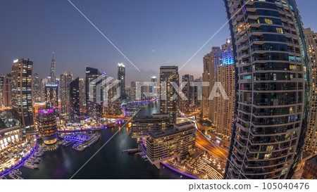 Aerial view to Dubai marina skyscrapers around canal with floating boats day to night timelapse 105040476