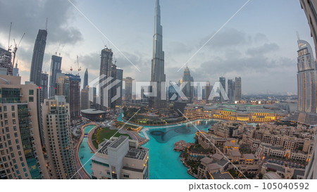 Skyscrapers rising above Dubai downtown day to night timelapse surrounded by modern buildings aerial top view Skyscrapers rising above Dubai downtown day to night timelapse surrounded by modern buildings aerial top view 105040592