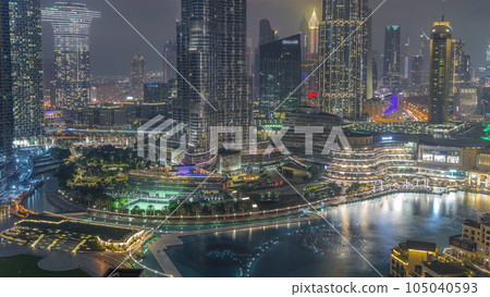 Skyscrapers rising above Dubai downtown day to night timelapse surrounded by modern buildings aerial top view Skyscrapers rising above Dubai downtown day to night timelapse surrounded by modern buildings aerial top view 105040593