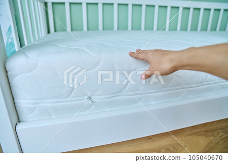 Close-up of woman's hand touches mattress on children's bed Close-up of woman's hand touches mattress on children's bed 105040670