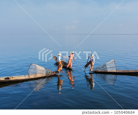Myanmar travel attraction landmark - three traditional Burmese fishermen with fishing nets on boats at Inle lake in Myanmar famous for their distinctive one legged rowing style Myanmar travel attraction landmark - three traditional Burmese fishermen with fishing nets on boats at Inle lake in Myanmar famous for their distinctive one legged rowing style 105040684