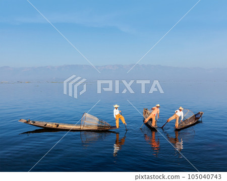 Myanmar travel attraction landmark - Traditional Burmese fishermen with fishing nets on boats at Inle lake in Myanmar famous for their distinctive one legged rowing style Myanmar travel attraction landmark - Traditional Burmese fishermen with fishing nets on boats at Inle lake in Myanmar famous for their distinctive one legged rowing style 105040743