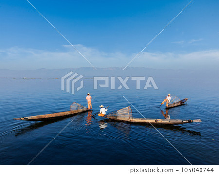 Myanmar travel attraction landmark - Traditional Burmese fishermen with fishing nets on boats at Inle lake in Myanmar famous for their distinctive one legged rowing style 105040744