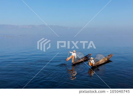 Myanmar travel attraction landmark - Traditional Burmese fishermen with fishing net at Inle lake in Myanmar famous for their distinctive one legged rowing style Myanmar travel attraction landmark - Traditional Burmese fishermen with fishing net at Inle lake in Myanmar famous for their distinctive one legged rowing style 105040745