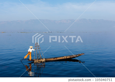 Myanmar travel attraction landmark - Traditional Burmese fisherman balancing with fishing net at Inle lake, Myanmar famous for their distinctive one legged rowing style 105040751