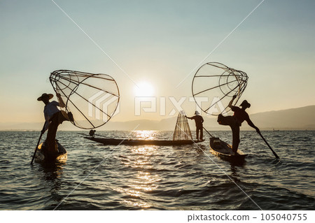Myanmar travel attraction landmark - three traditional Burmese fishermen at Inle lake, Myanmar famous for their distinctive one legged rowing style Myanmar travel attraction landmark - three traditional Burmese fishermen at Inle lake, Myanmar famous for their distinctive one legged rowing style 105040755