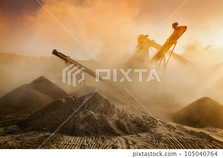 Industrial hell pollution background concept - crusher rock stone crushing machine at open pit mining and processing plant for crushed stone, sand and gravel on sunset Industrial hell pollution background concept - crusher rock stone crushing machine at open pit mining and processing plant for crushed stone, sand and gravel on sunset 105040764