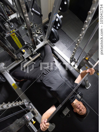 A man doing muscle training at a sports gym A man doing muscle training at a sports gym 105041754