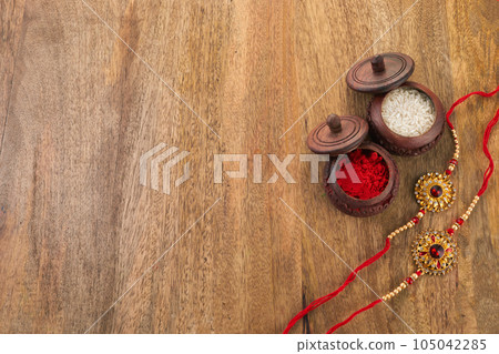 Raksha Bandhan background with Rakhi string, Rice Grains and Kumkum 105042285