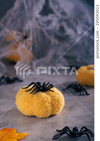 Halloween spider on a handmade knitted pumpkin on a cobweb background vertical view Halloween spider on a handmade knitted pumpkin on a cobweb background vertical view 105043013
