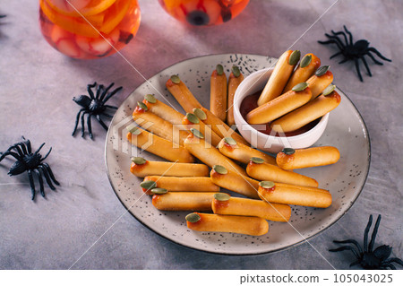 Halloween savory breadsticks with pumpkin seed nails on ketchup on a plate 105043025