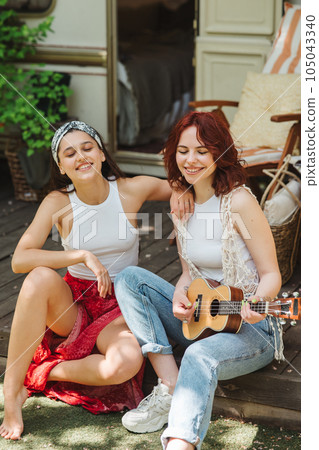Happy hippie friends are having a good time together with guitar in camper trailer. Holiday, vacation, trip concept. 105043340