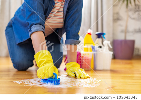Woman in rubber gloves is using floor brush to cleaning floor Woman in rubber gloves is using floor brush to cleaning floor 105043345