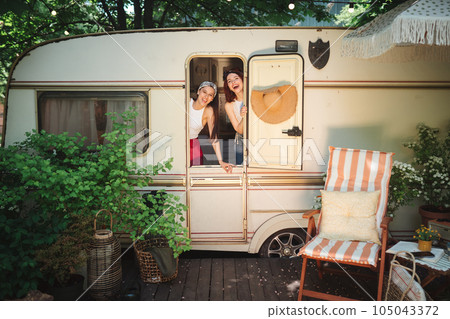 Happy hippie friends are having a good time together in a camper trailer. Holiday, vacation, trip concept. 105043372