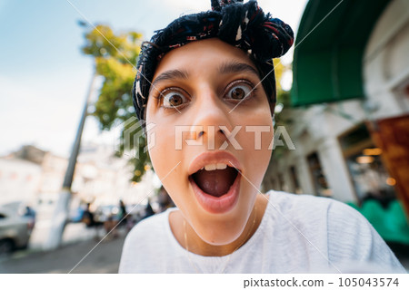 Close up of attractive young woman standing shocked, surprised outdoor 105043574